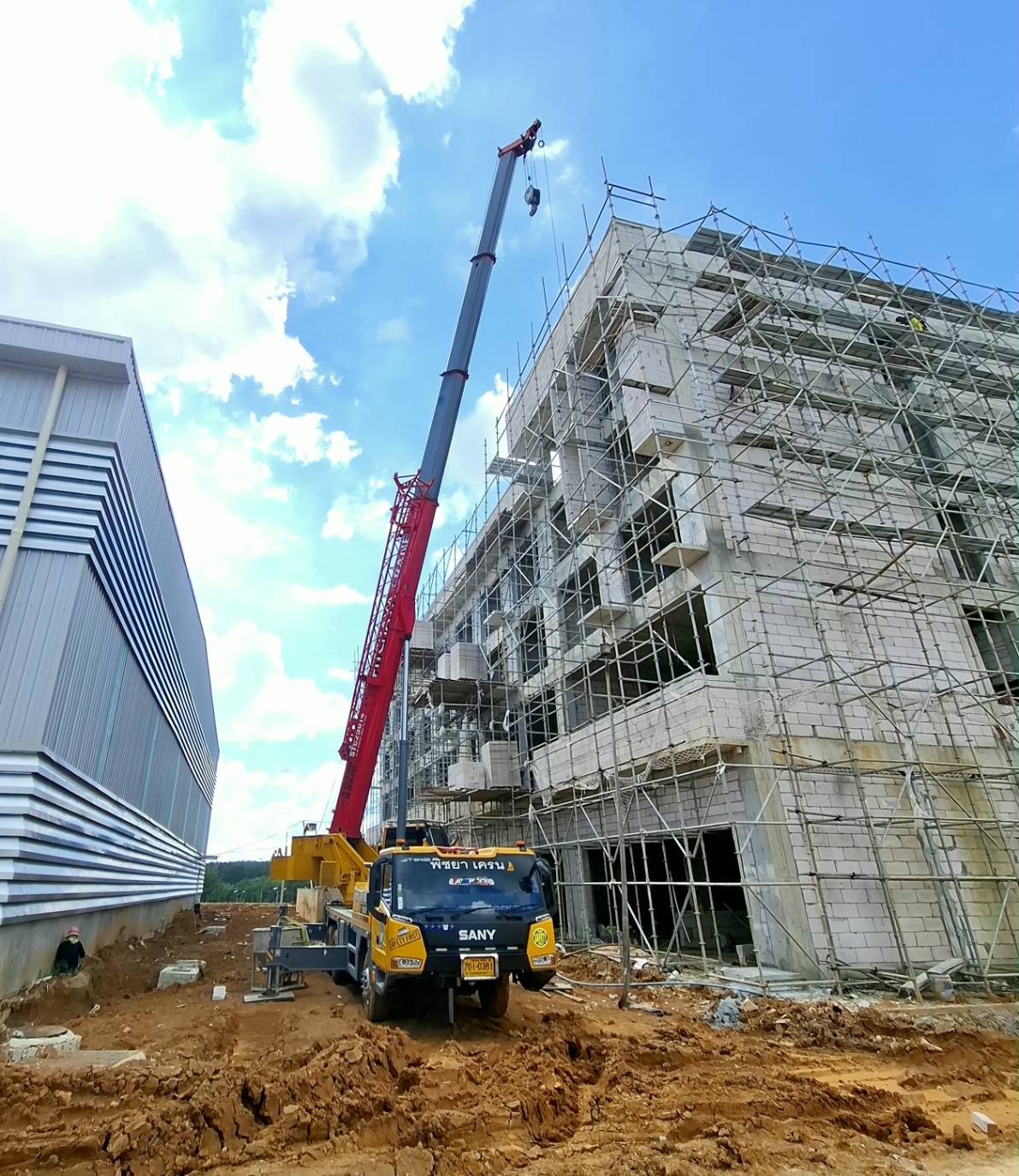 รถเครนปลวกแดงกำลังยกวัสดุก่อสร้างในไซต์งาน